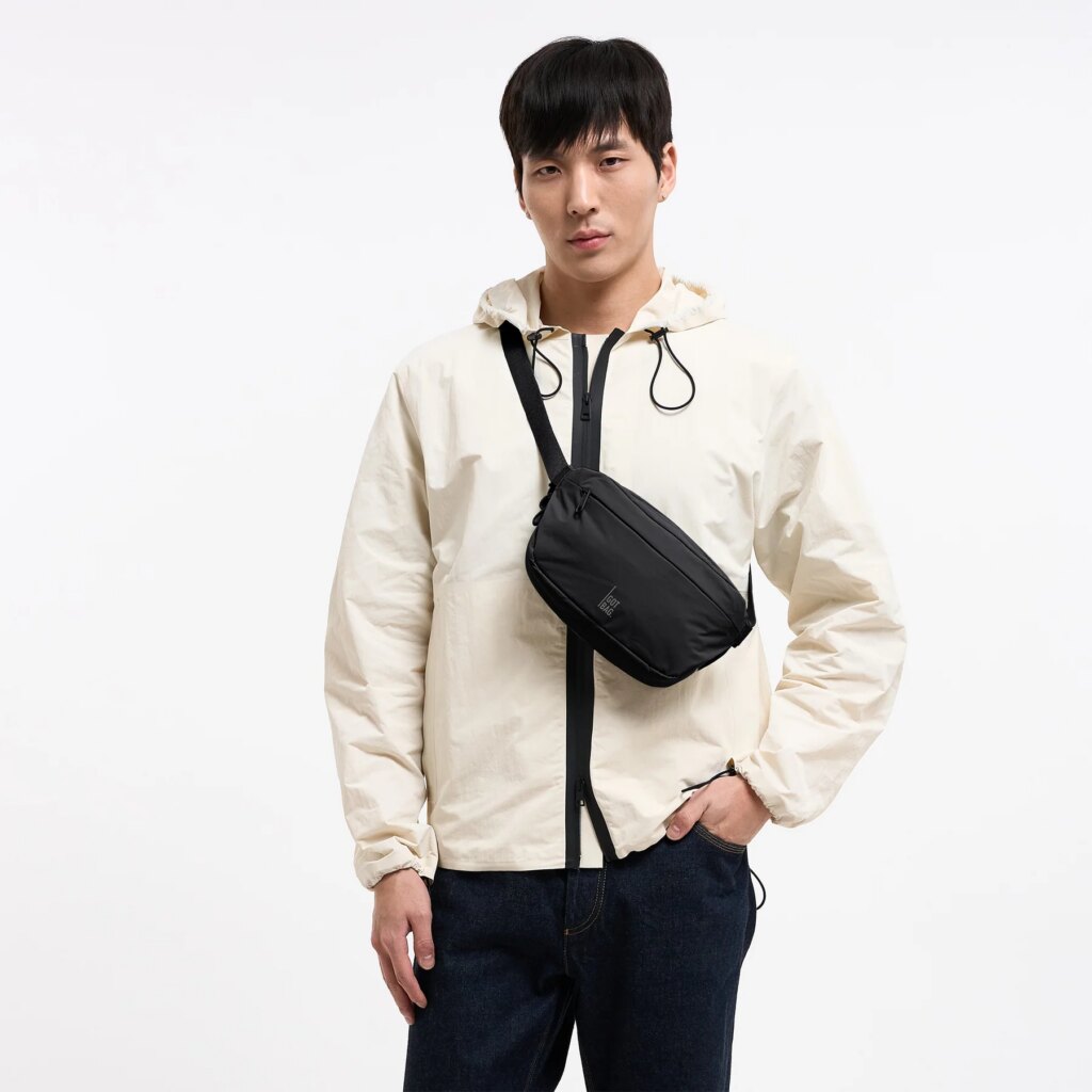 ADAPT SLING BAG Tasche in black (Schwarz) von einem Mann crossbody getragen.