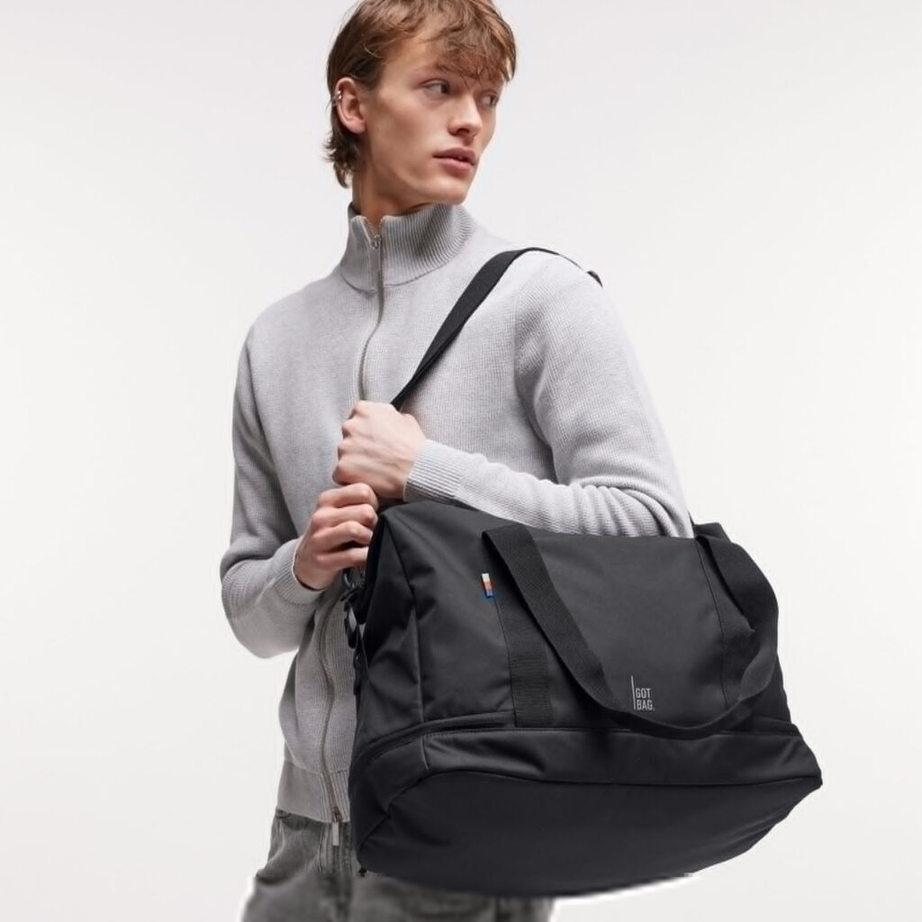 WEEKEND BAG Tasche in black (Schwarz) von einem Mann über der Schulter getragen.