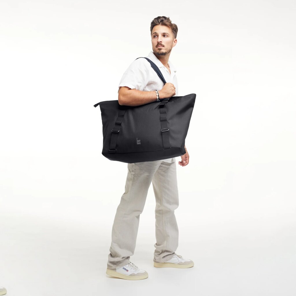 TOTE BAG MONOCHROME EDITION Tasche in black (Schwarz) von einem Mann über der Schulter getragen.