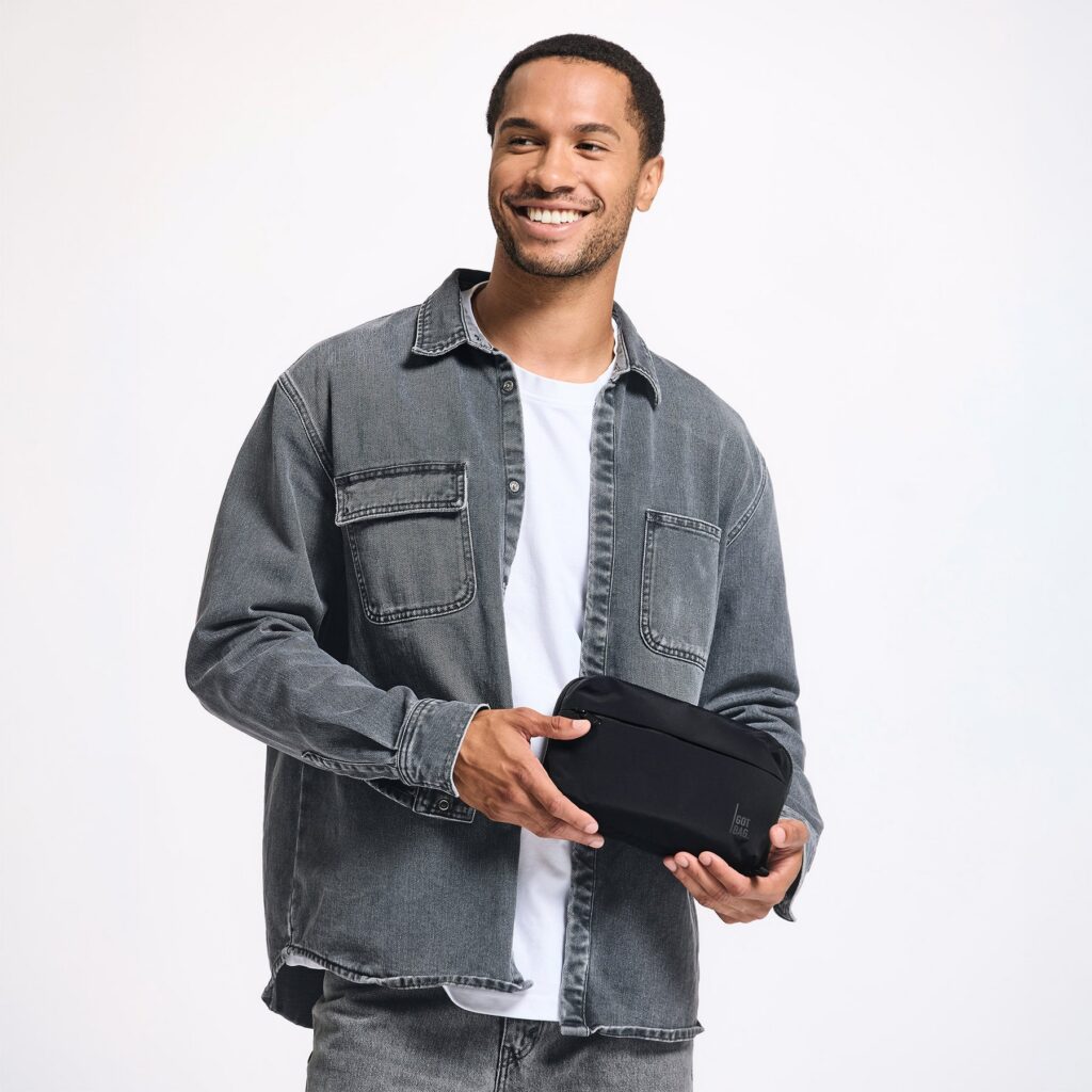 COMMUTER TECH POUCH Accessoire in black (Schwarz) von einem Mann in der Hand gehalten.