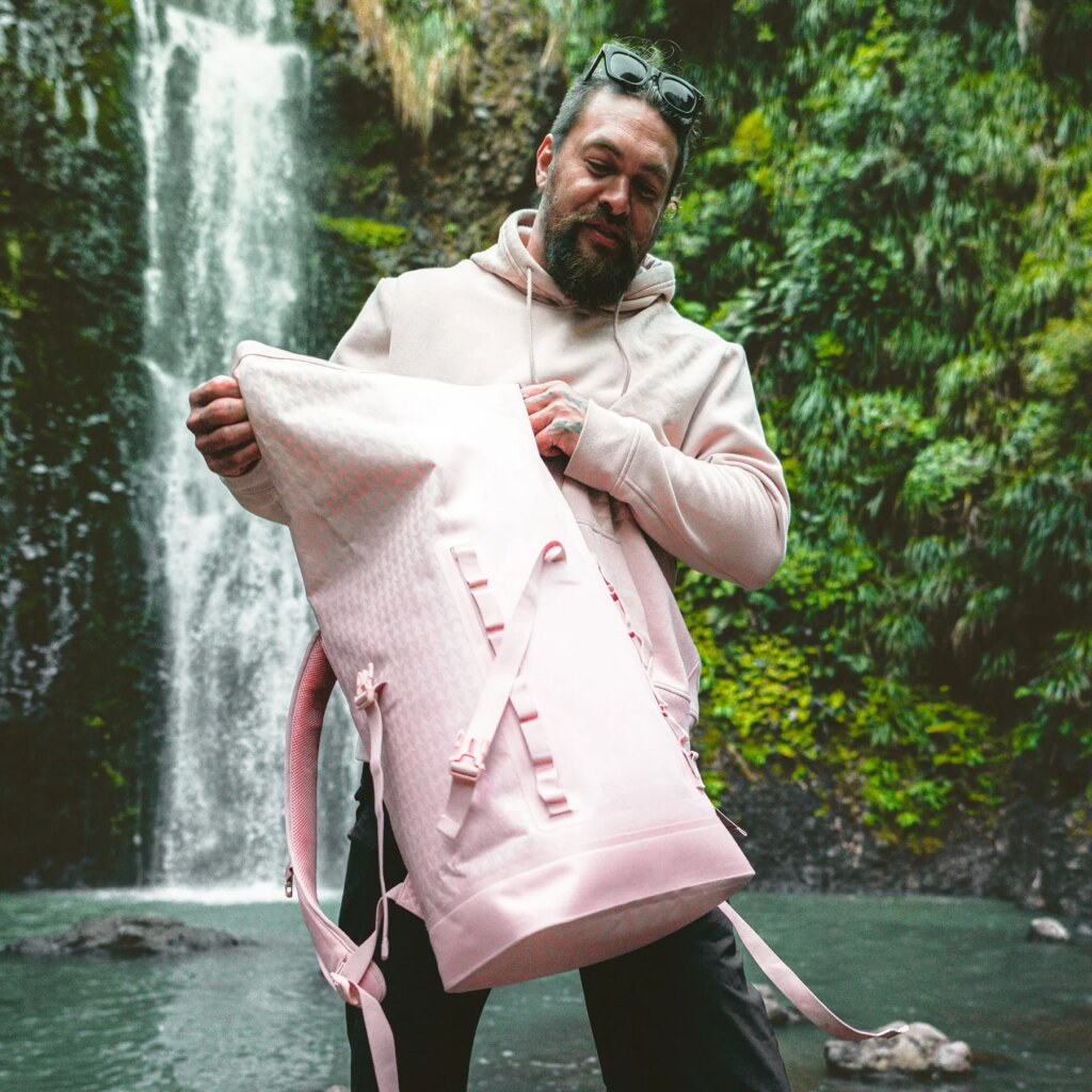 ROLLTOP ON THE ROAM Rucksack in dirty pink, von einem Mann gehalten und geöffnet.