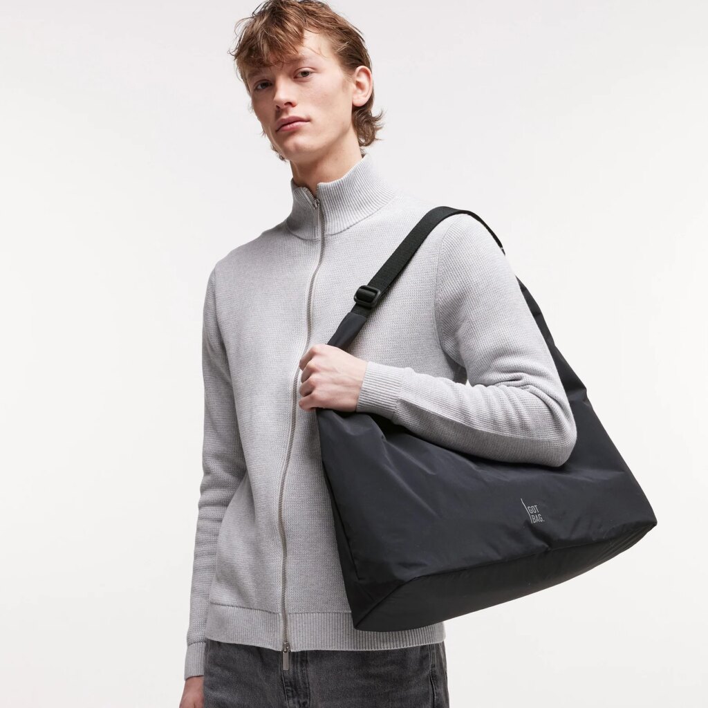 T SHAPE BAG Tasche in black (Schwarz) von einem Mann über der Schulter getragen.