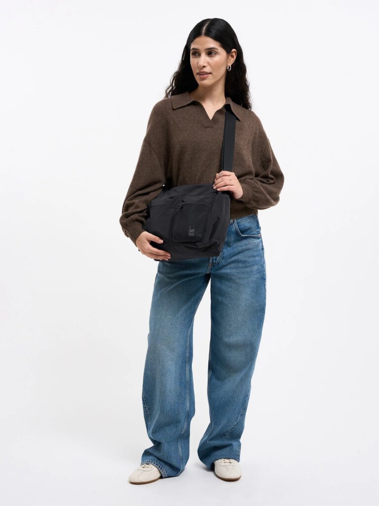 POCKET SLING BAG Tasche in black (Schwarz) von einer Frau crossbody getragen.