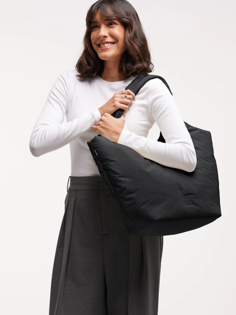 CLOUD TOTE BAG gepolsterte Tasche in sea lemon (zartes Pastellgelb) von einer Frau über der Schulter getragen.