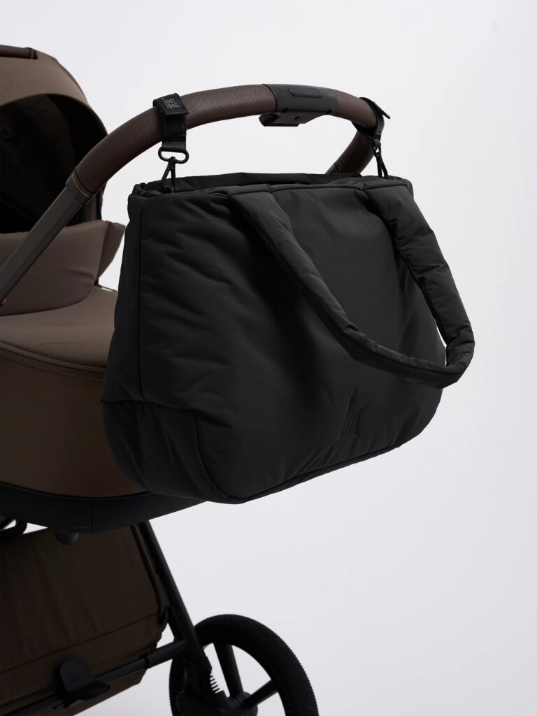 CLOUD HORIZON TOTE BAG Tasche in black (Schwarz), mit Gurten an einem Kinderwagen befestigt.