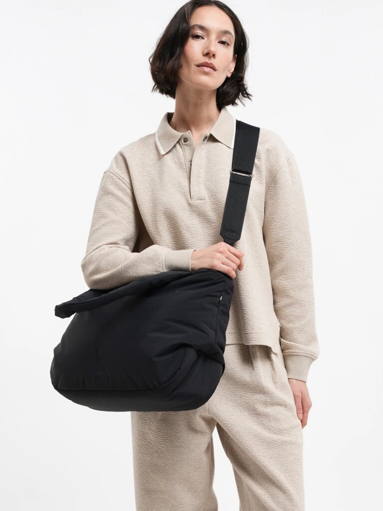 CLOUD HORIZON TOTE BAG Tasche in black (Schwarz) von einer Frau über der Schulter getragen.
