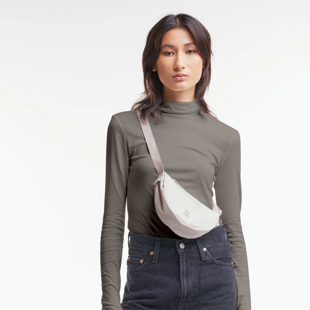 MOON BAG MINI Tasche in soft shell (warmes Cremeweiß) von einer Frau crossbody getragen.