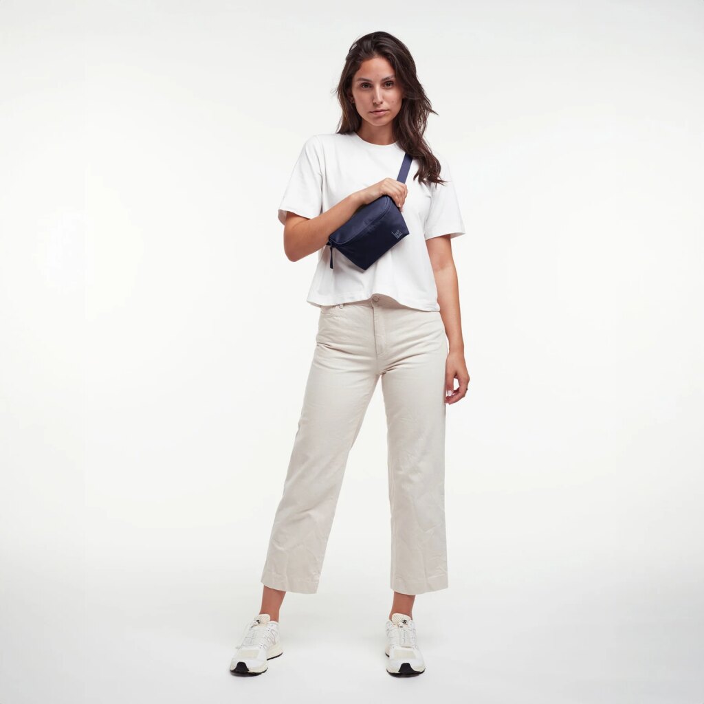 HIP BAG Tasche in tide (tiefes Dunkelblau mit Lilastich) von einer Frau crossbody getragen.