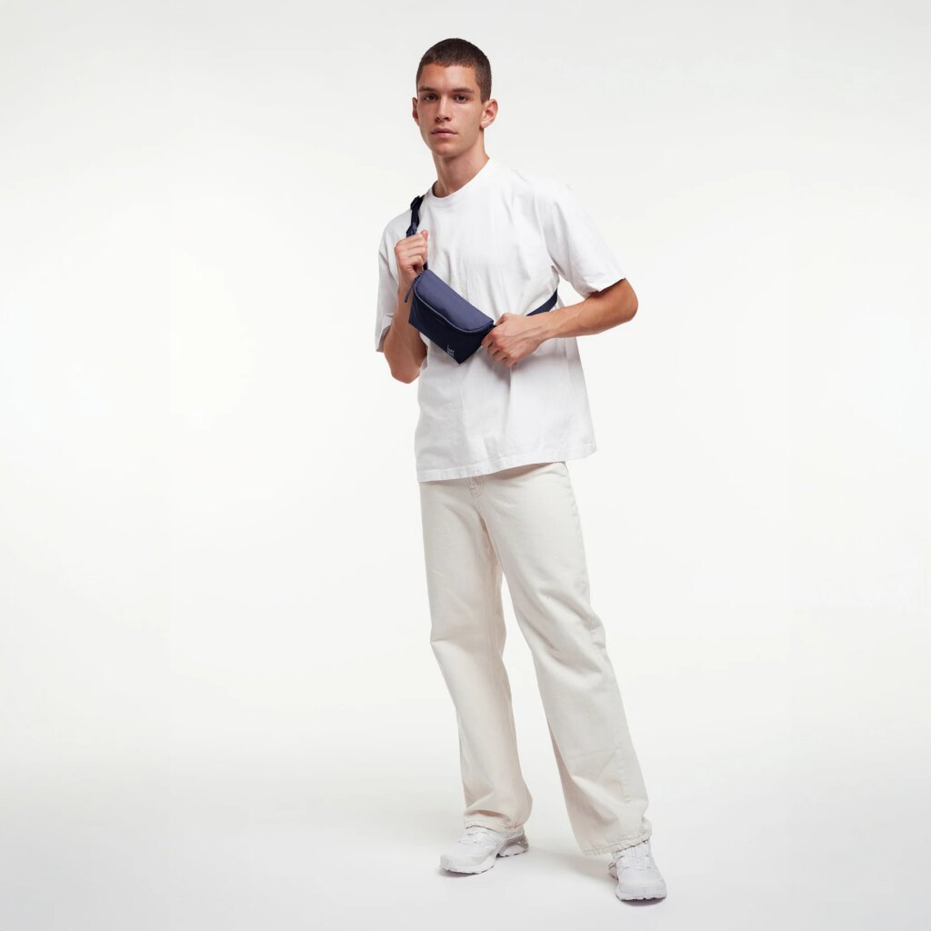 HIP BAG Tasche in tide (tiefes Dunkelblau mit Lilastich) von einem Mann crossbody getragen.